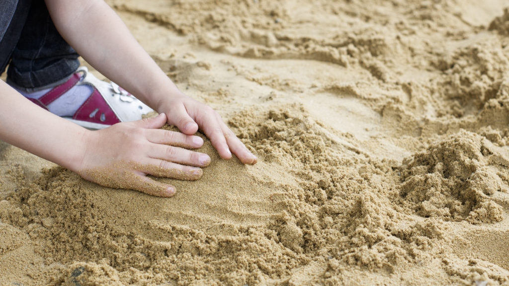 the child is building a tower of sand on the seashore