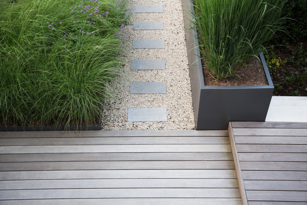 A beautiful landscaping job with grass, gravel, and wood panels