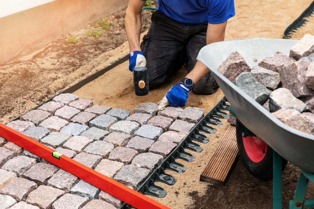 a homeowner adding a brick pathway to his home DIY landscaping