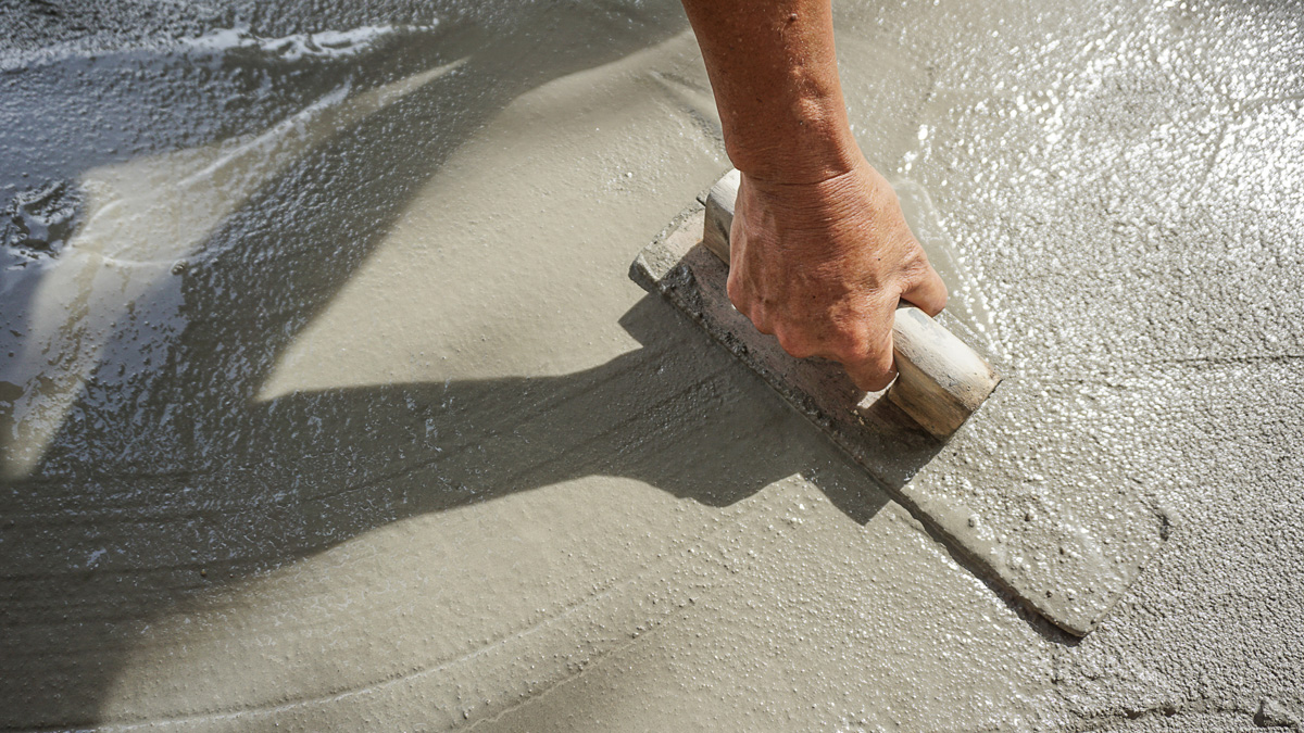 A person’s hand using a tool to smooth wet concrete in Hobbs.